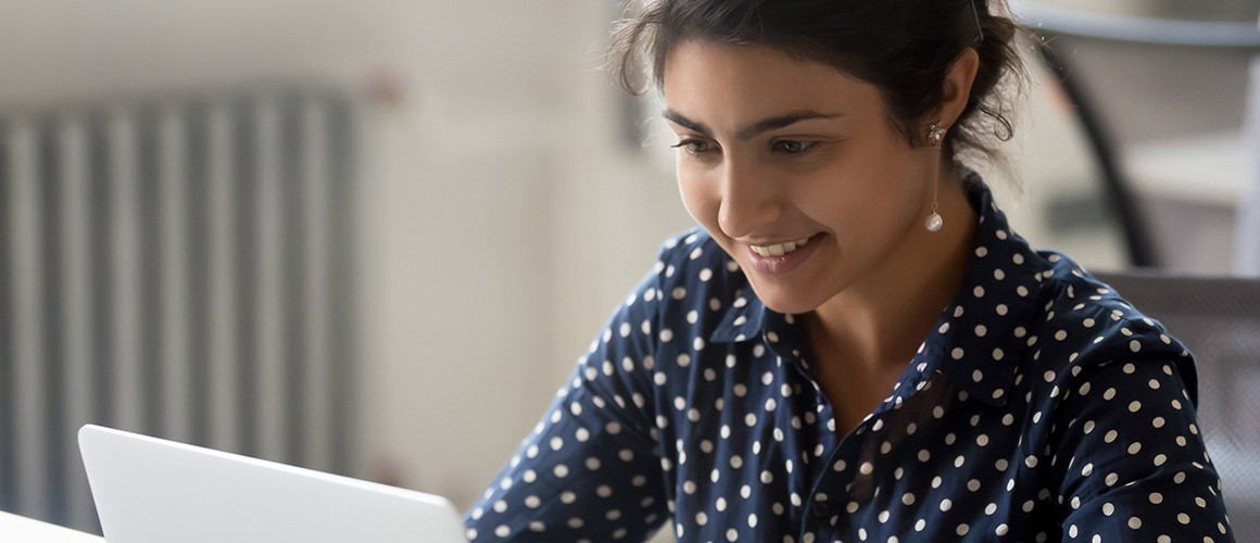 Woman smiling while working on a laptop